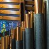Closeup of copper-topped organ pipes and exterior organ casing, seen from inside the Bigelow organ at Saint Ambrose Church, with stained glass window in the background.